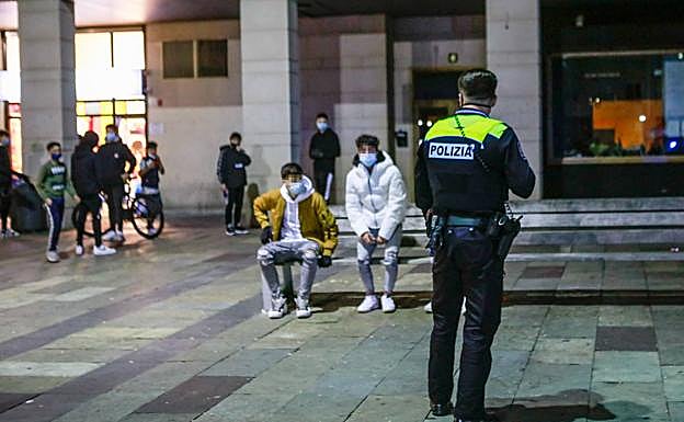 Un agente local habla con dos jóvenes en la plaza de Zumaia. 