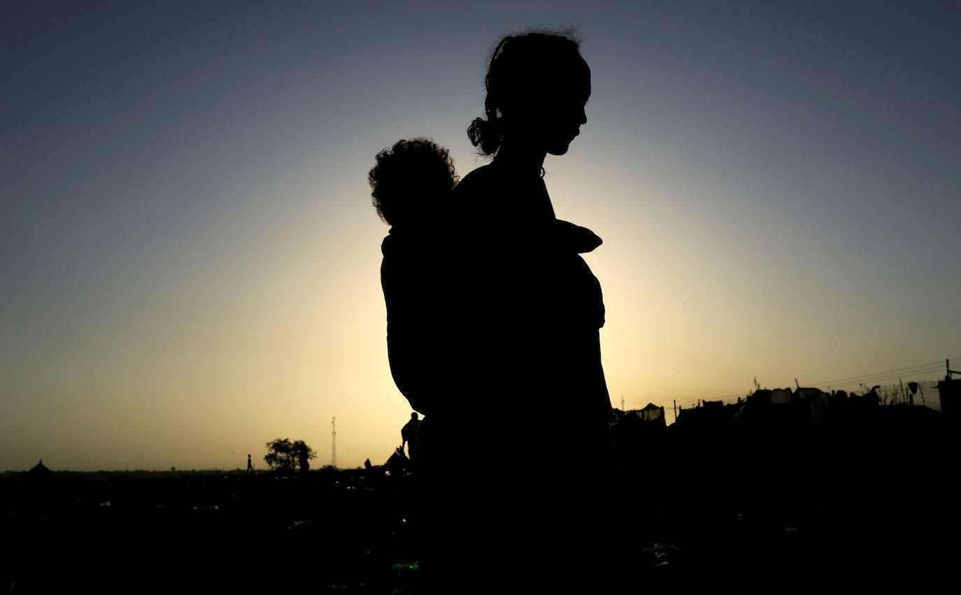 Una mujer etíope que huyó de los combates en curso en la región de Tigray, lleva a su hijo cerca del río Setit en la frontera entre Sudán y Etiopía en la aldea de Hamdayet en el estado oriental de Kassala.