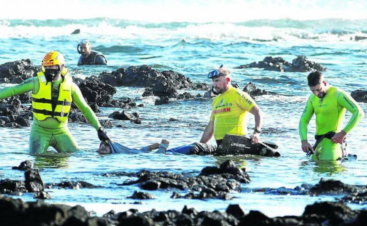 Una tragedia diaria. Miembros de los equipos de salvamento trasladan ayer el cadáver de un hombre después de hundirse la barca en la que viajaba con otras 34 personas frente a la costa de Orzola, en el norte de la isla canaria de Lanzarote. Ocho migrantes murieron y 27 pudieron ser rescatados el martes por la noche. 