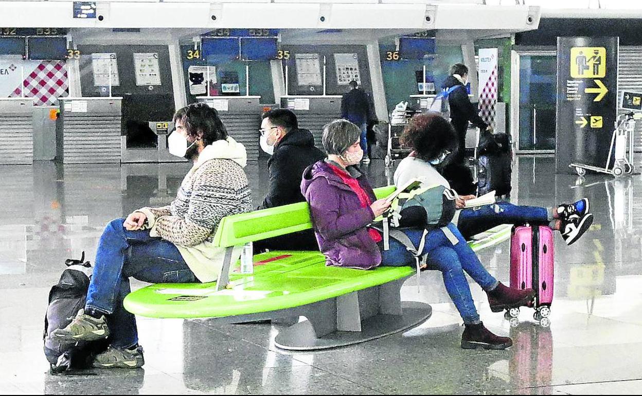 Varios pasajeros aguardaban ayer por la tarde el momento de embarcar en su vuelo, en la zona de Salidas del aeropuerto de Loiu. 