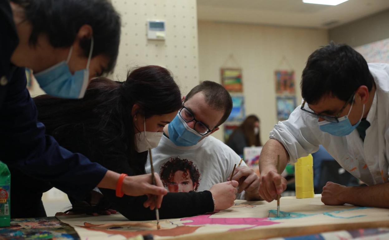 Voluntarios participan en el taller de pintura de la asociación de parálisis cerebral Aspace. 