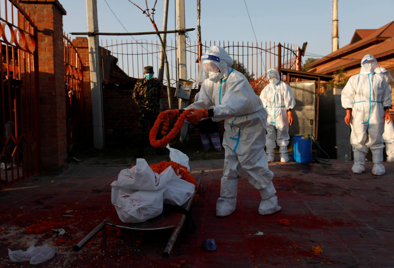 Una mujer soldado con equipo de protección personal (EPP) ofrece una guirnalda en el cuerpo de una víctima de coronavirus proporcionada por los familiares en el crematorio, en medio de la propagación de la enfermedad del coronavirus (COVID-19), en Katmandú, Nepal.