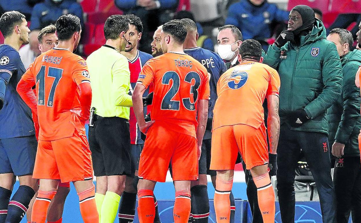 Los jugadores del Basaksehir, de naranja, y del PSG rodean al árbitro tras escuchar insultos racistas.