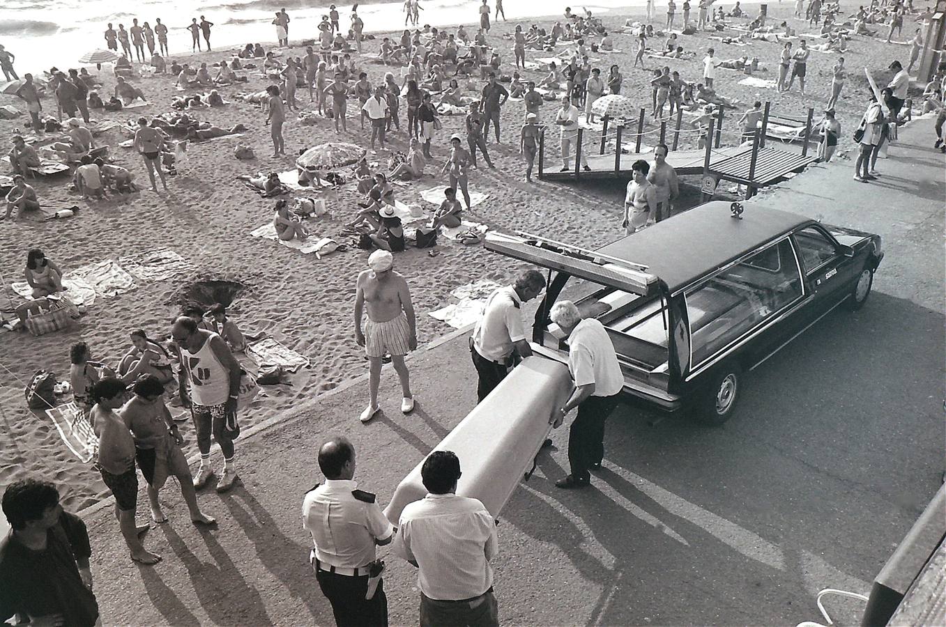 Empleados de una empresa funeraria retiran el cuerpo de un hombre fallecido de un infarto en la playa de Ereaga.