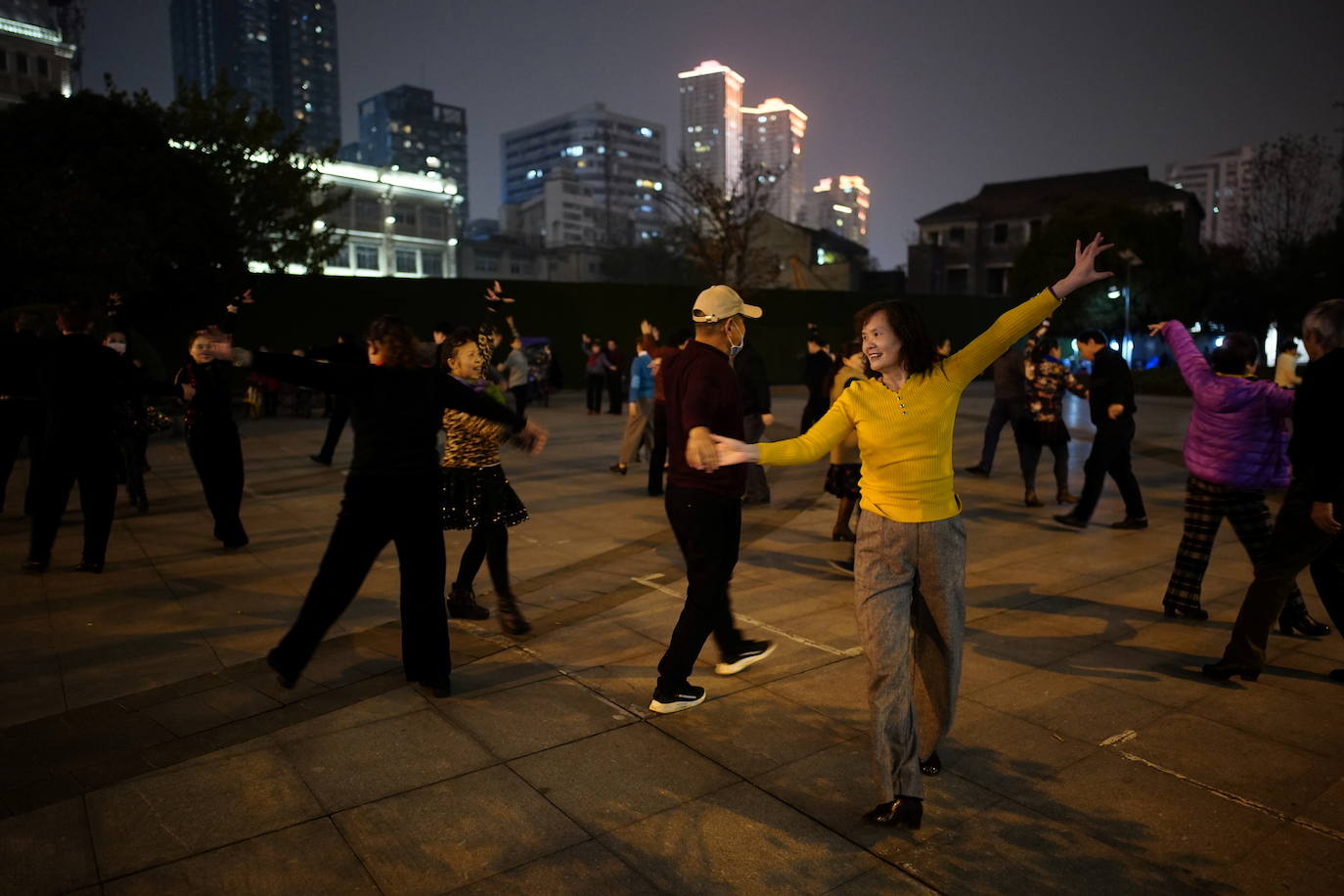 Decenas de personas bailan en un parque a media noche.