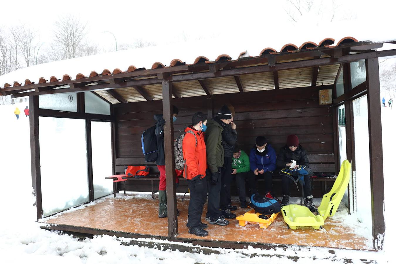 Varios adolescentes descansan tras jugar con sus trineos.