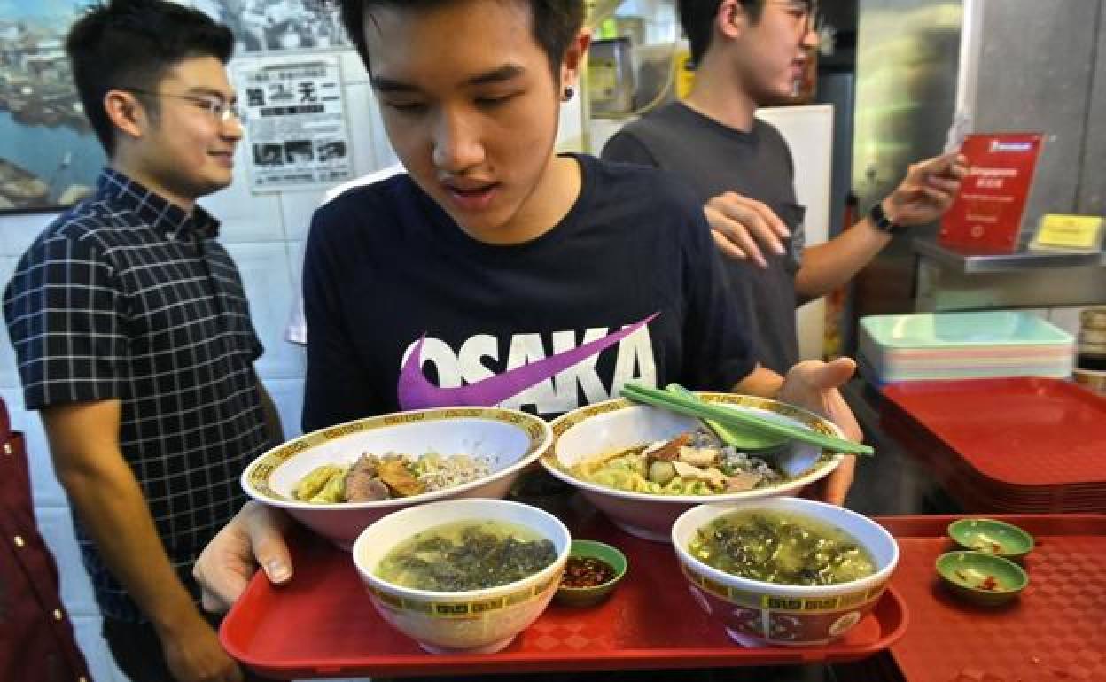 El cliente de un hawker de Singapur lleva una bandeja de comida.