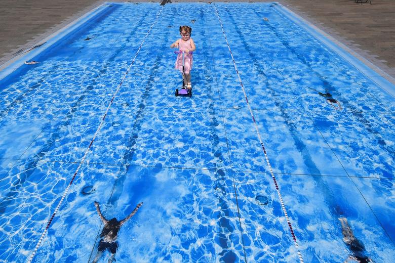 Eliza, de 3 años, se desliza sobre una obra de arte temporal que representa una piscina en Londres, Gran Bretaña.