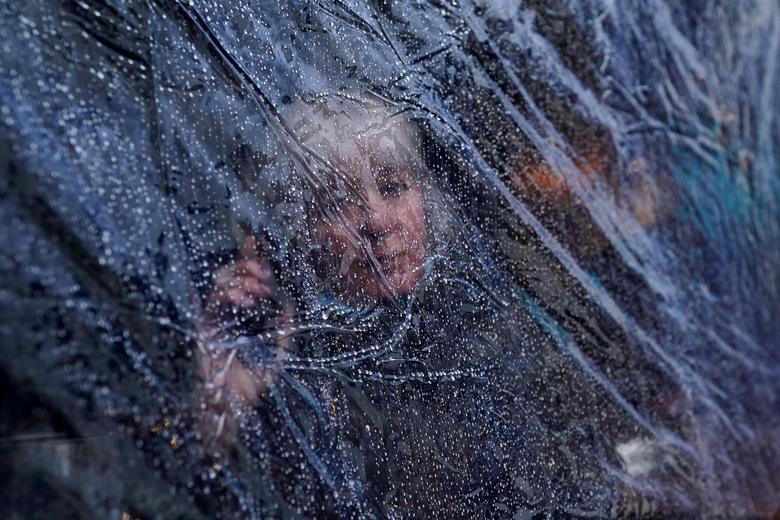 Gotas de lluvia en las láminas de plástico que rodean a una mujer en la terraza de una cafetería de Galway, Irlanda.