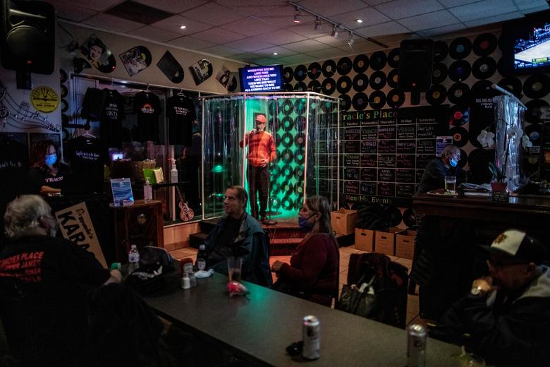 Un hombre canta dentro de una 'cabina de ducha' improvisada para proteger a los clientes en el restaurante y karaoke Tracie's Place en Hamilton, Canadá.