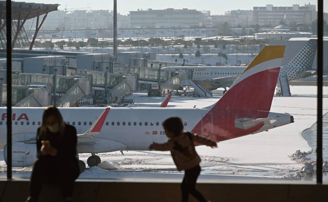 Una madre y un niño esperan su vuelo en un Barajas aún congelado