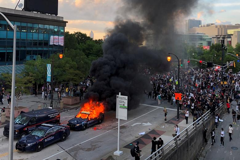 Un coche de la policía de Atlanta se quema mientras la gente protesta contra la muerte de Floyd.