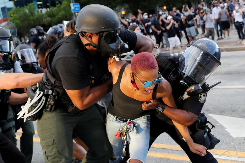 Un manifestante es detenido por agentes de policía durante una protesta.