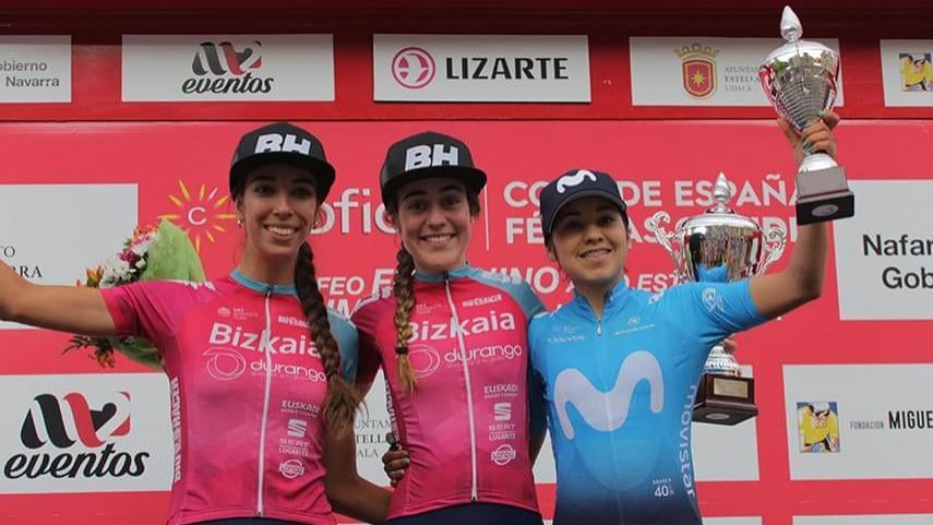 Enara López, en el medio, en el podio de una carrera ciclista. 