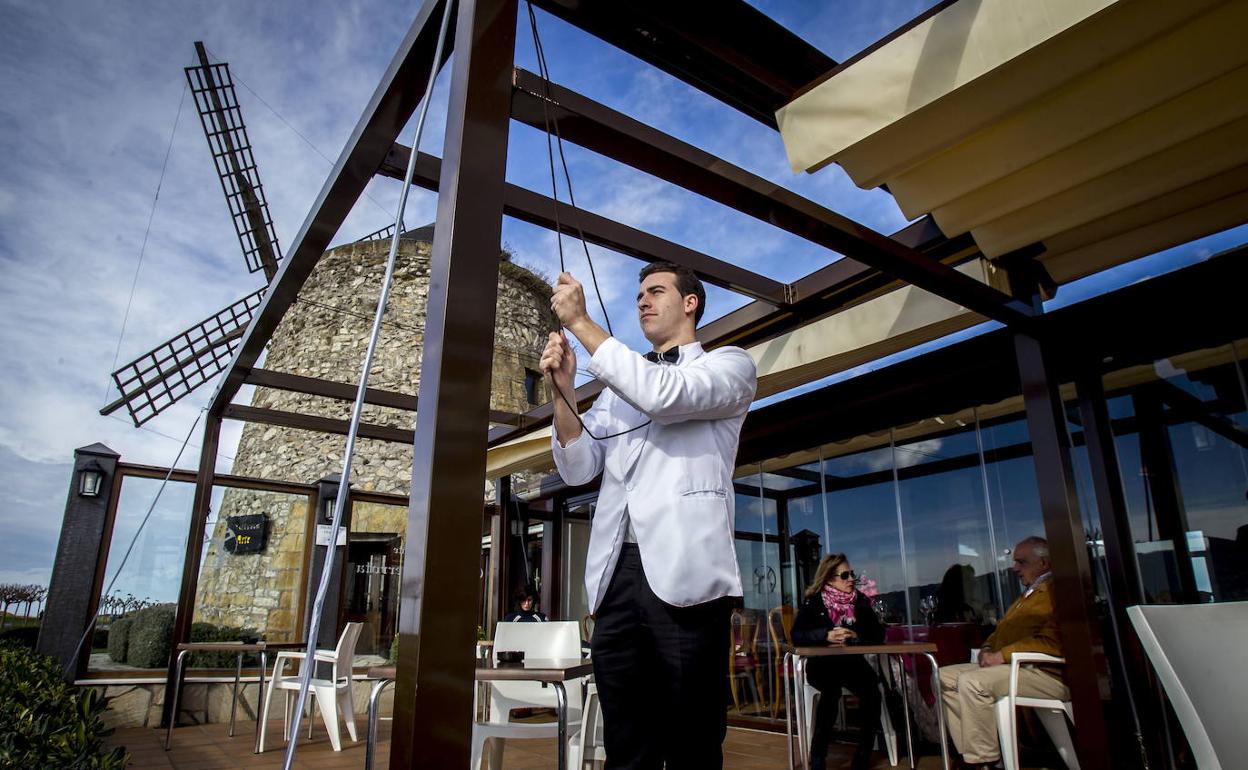 Un camarero retira el toldo del restaurante Cubita, ubicado junto al molino de Aixerrota.