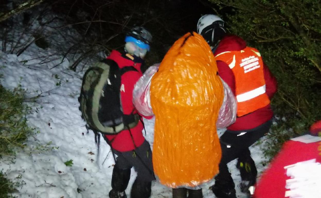 La mujer, protegida del frío es acompañada por miembros del equipo de rescate. 