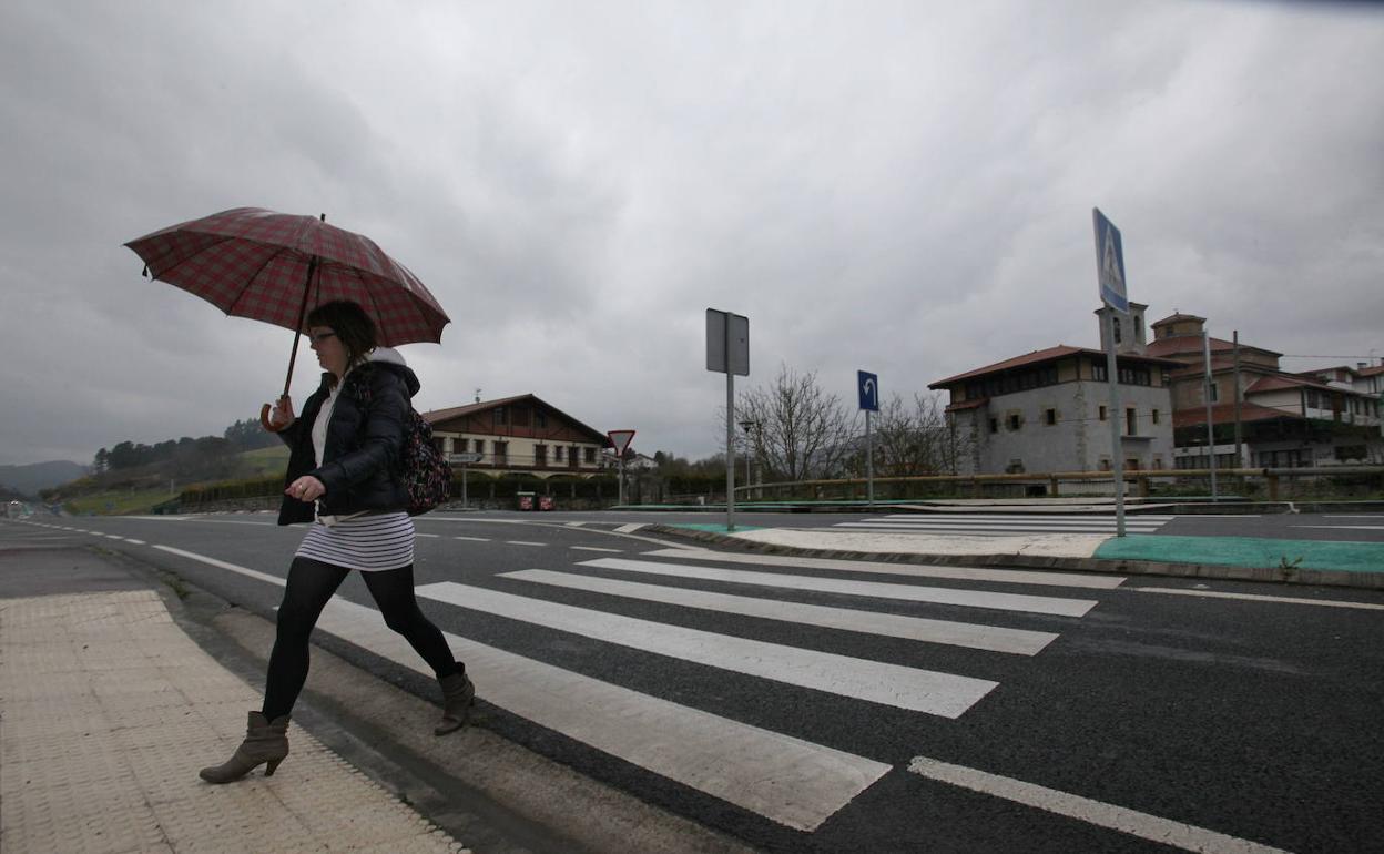 Una mujer cruza la carretera con el centro de Murueta al fondo.