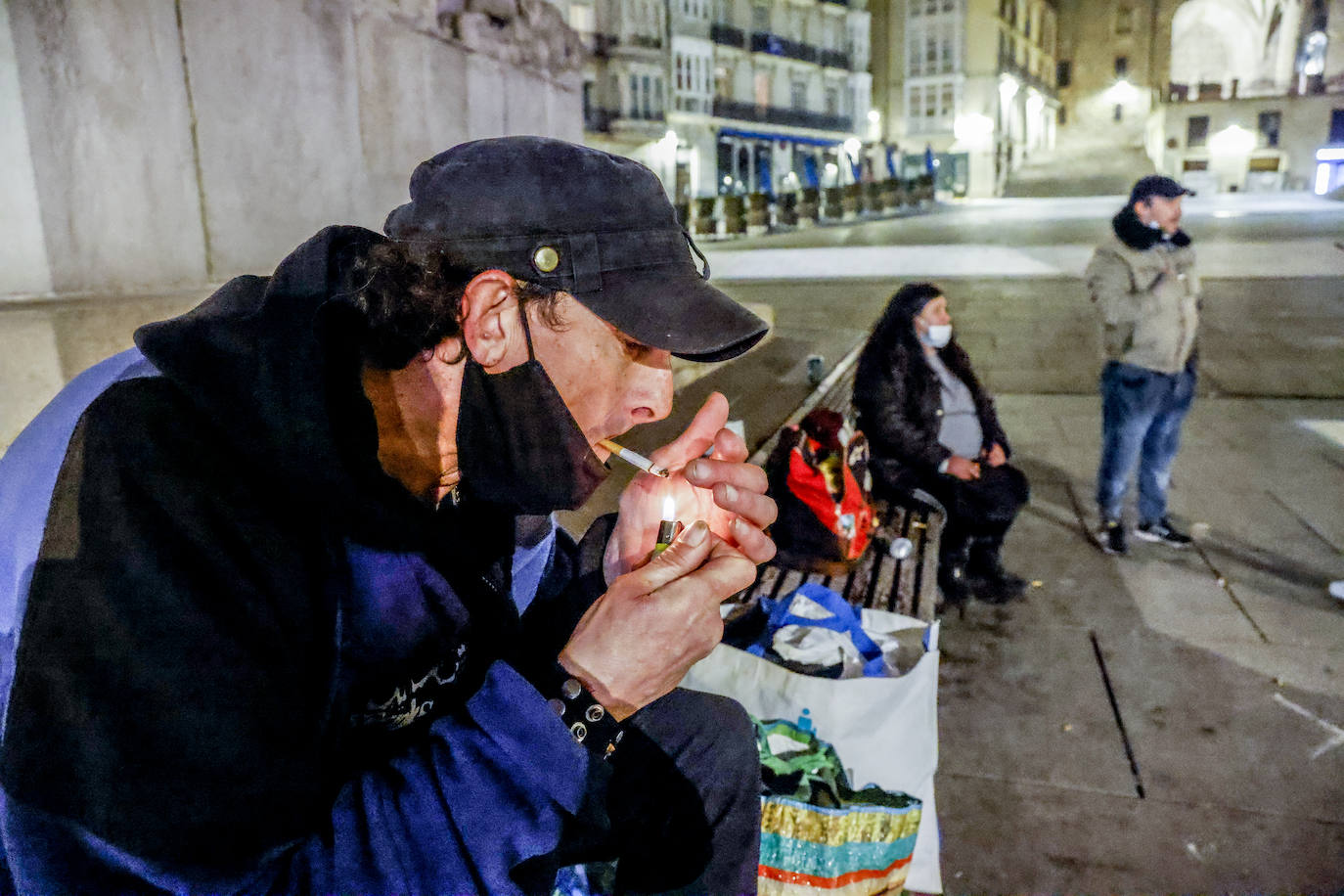 Armando Fernández se enciende un cigarro en la plaza de la Virgen Blanca antes de recoger sus cosas e irse a dormir al albergue municipal.