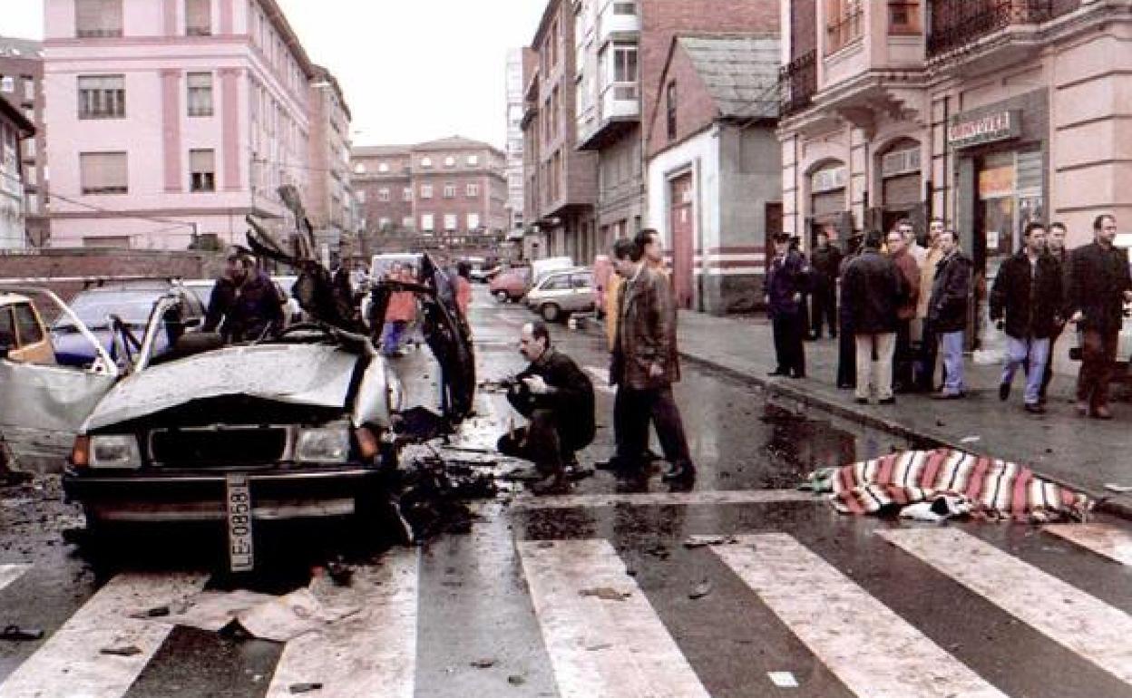 El coche que conducía el comandante asesinado, cuyo cuerpo permanece en la calzada, a la espera de ser trasladado, cubierto por una manta. 