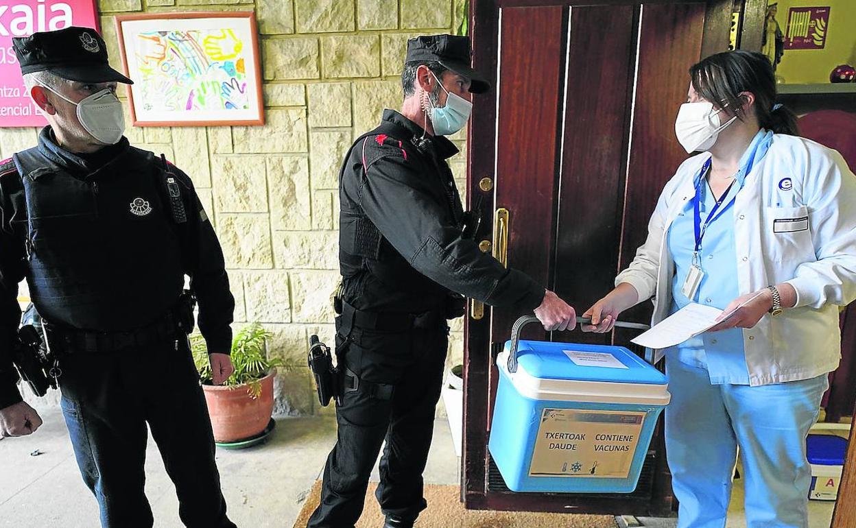 Agentes de la Ertzaintza hacen entrega de una nevera con vacunas contra el coronavirus en una residencia de mayores. 