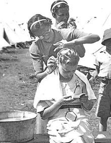 Imagen secundaria 2 - Unos pequeños muestran sus identificaciones. Niñas y niños forman dos colas para comer en el campamento de Stoneham, atendido por voluntarios. Un momento para arreglarse en Stoneham. 