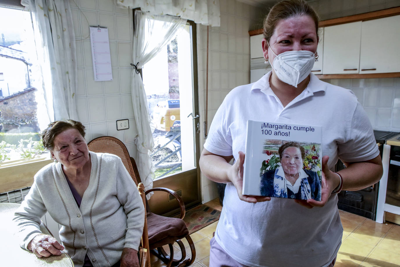 El mejor regalo para Margarita, la primera dosis de la vacuna, llega poco después de haber cumplido un siglo. En la foto, su cuidadora muestra un álbum con el resumen de su vida en imágenes