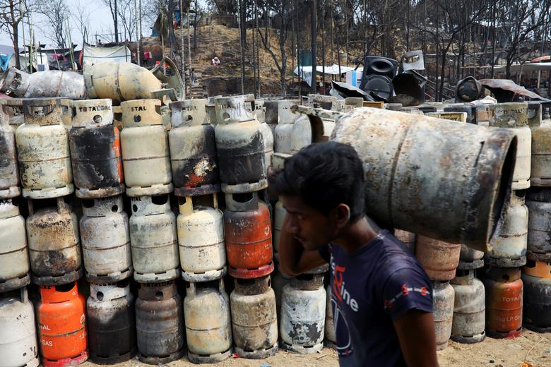 Un hombre rohingya recolecta cilindros de gas licuado de petróleo (GLP) dañados en un campo de refugiados después de un incendio masivo en Cox's Bazar.