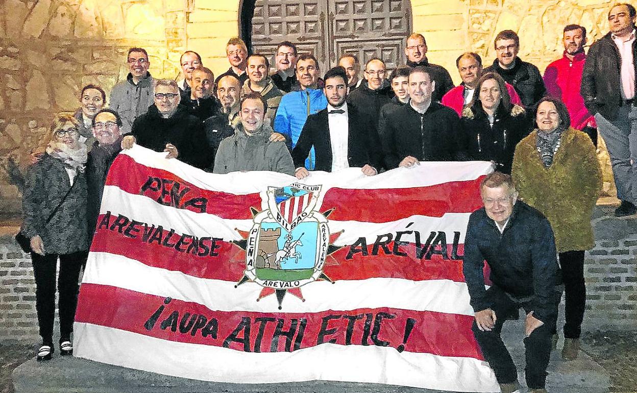 Los socios de la agrupación posan en una calle de Arévalo con una bandera rojiblanca con su logotipo.