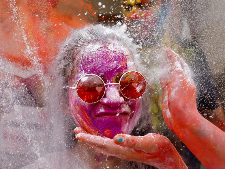 Una mujer reacciona mientras se aplica polvo en la cara durante las celebraciones de Holi en Ahmedabad, India.