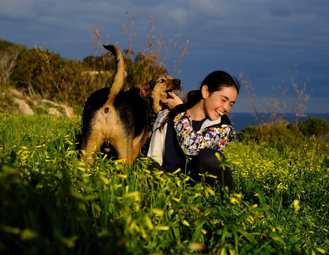 Una Rebecca de 12 años juega con Cookie, su perro, en las afueras del pueblo de Mellieha.