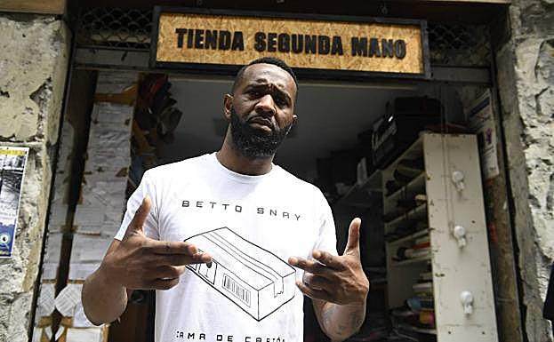 Betto Snay con la camiseta solidaria 'Cama de cartón' en la entrada de su tienda de segunda mano.