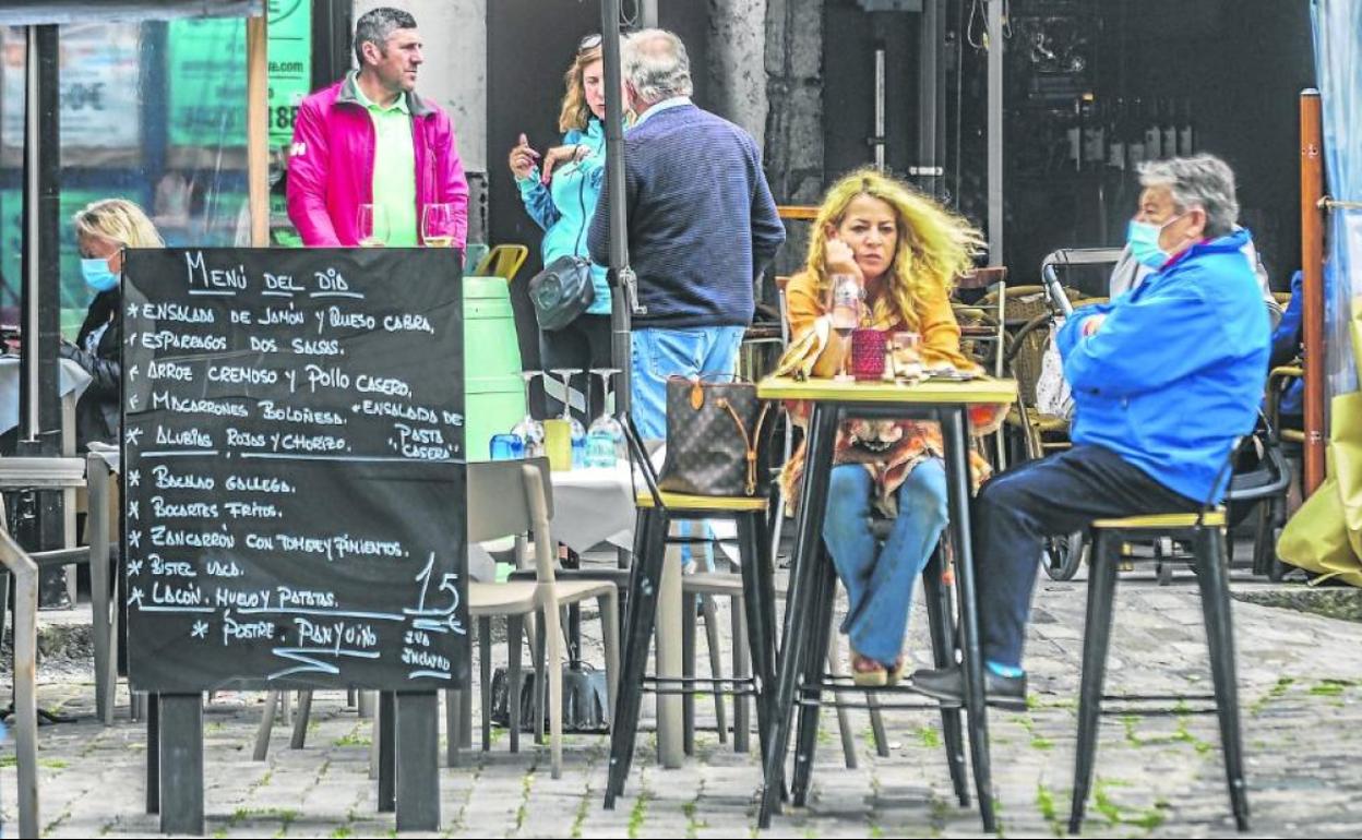Una pareja de clientes, en primer término, disfruta de una consumición en una terraza, ayer, en un establecimiento hostelero de Laredo. 
