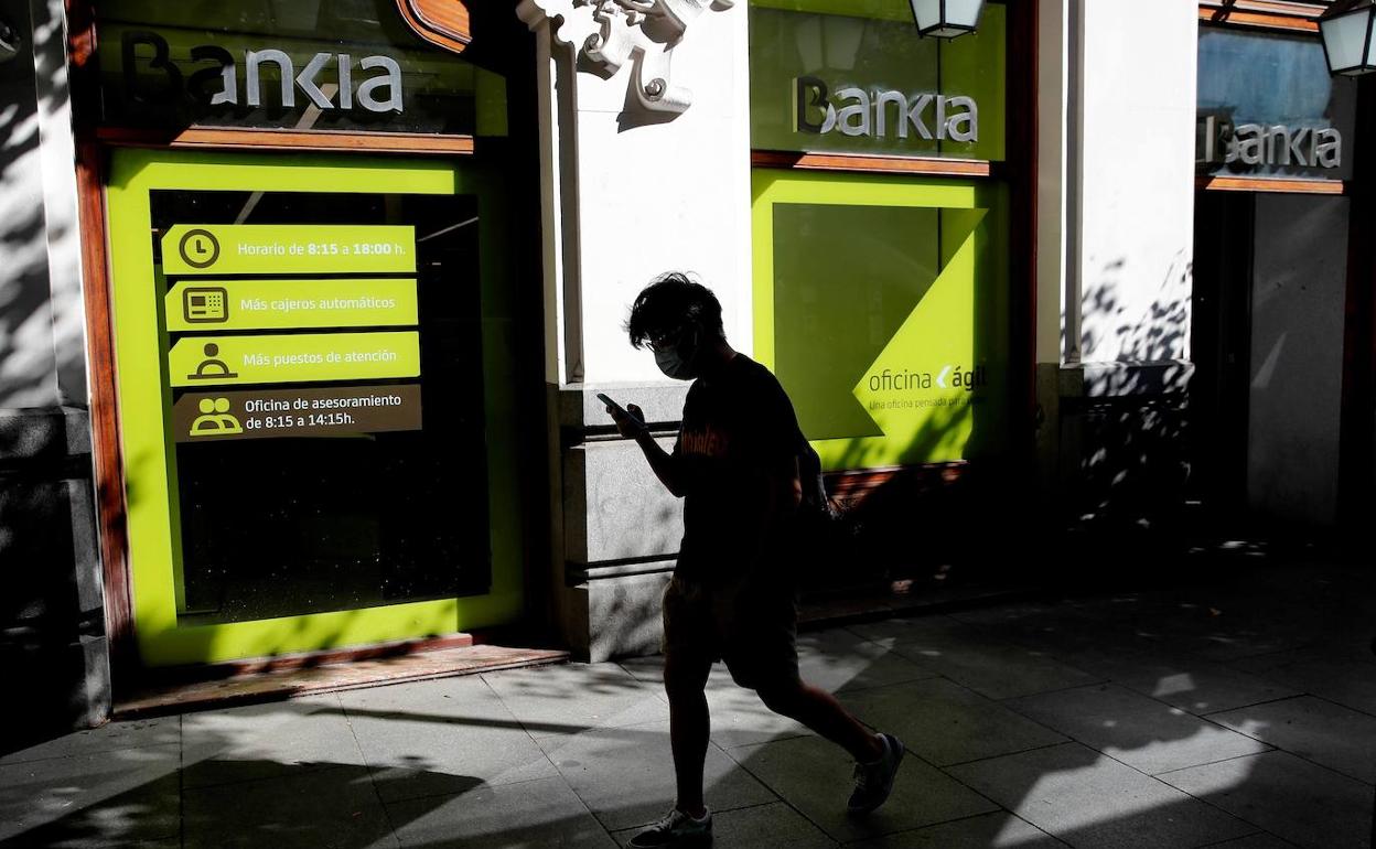 Un joven pasa frente a una sucursal de Bankia.