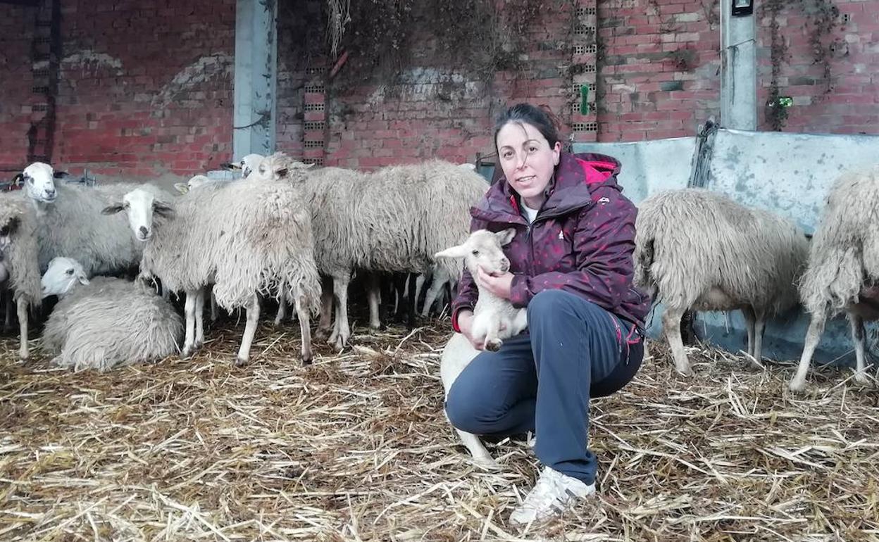 Eva García sostiene un cordero en el redil.