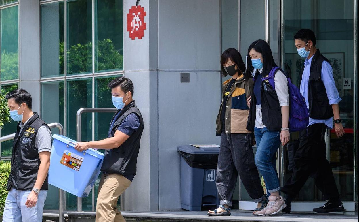 La policía de Hong Kong sale de periodico 'Apple Daily' con un detenido y cajas con material requisado.