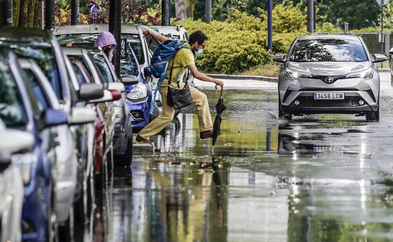 Un ciudadano intenta sortear los charcos que se crearon en los alrededores de la rotonda de América Latina fruto de la tormenta del 21 de junio.