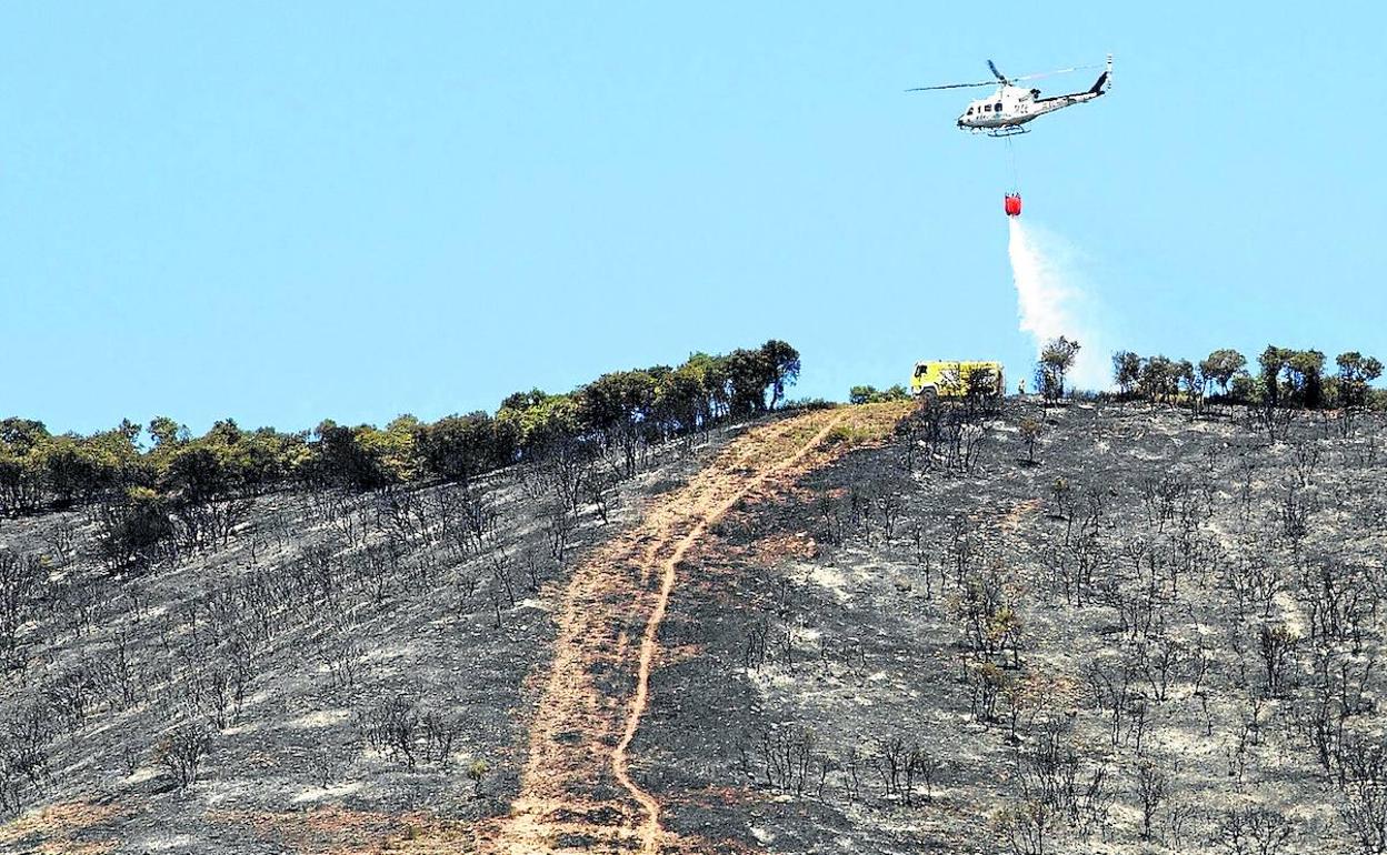 Un helicóptero lanza agua sobre uno de los perímetros del incendio para evitar que pueda propagarse. 