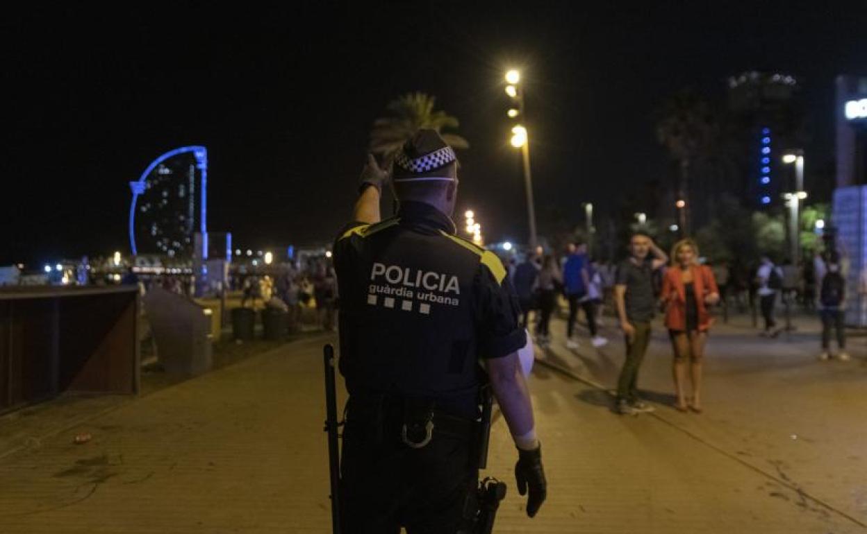 Un agente de la Guardia Urbana desaloja la playa de la Barceloneta. 