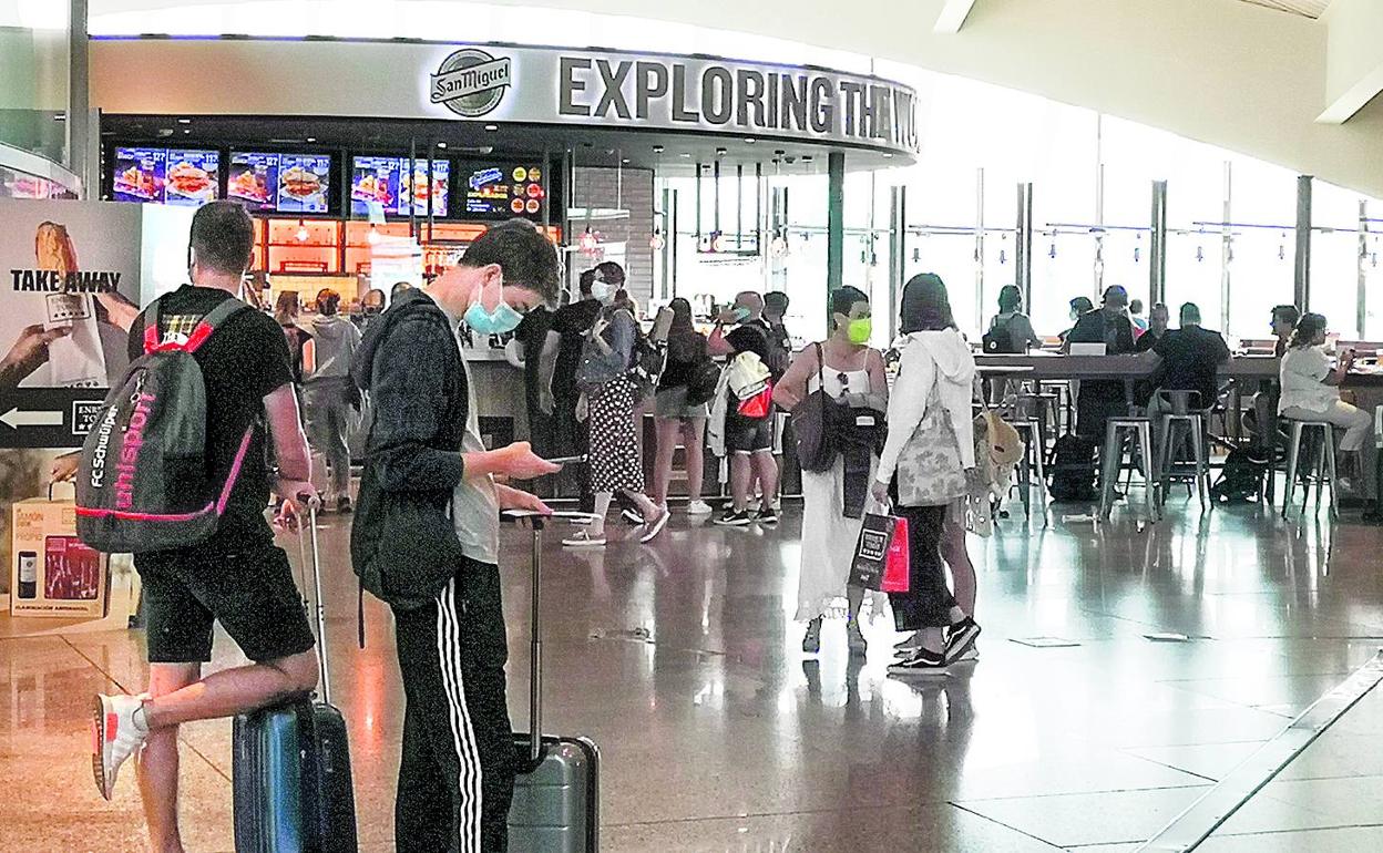 Varios pasajeros pasan por la zona de restauración del aeropuerto de Loiu antes de coger sus vuelos. 