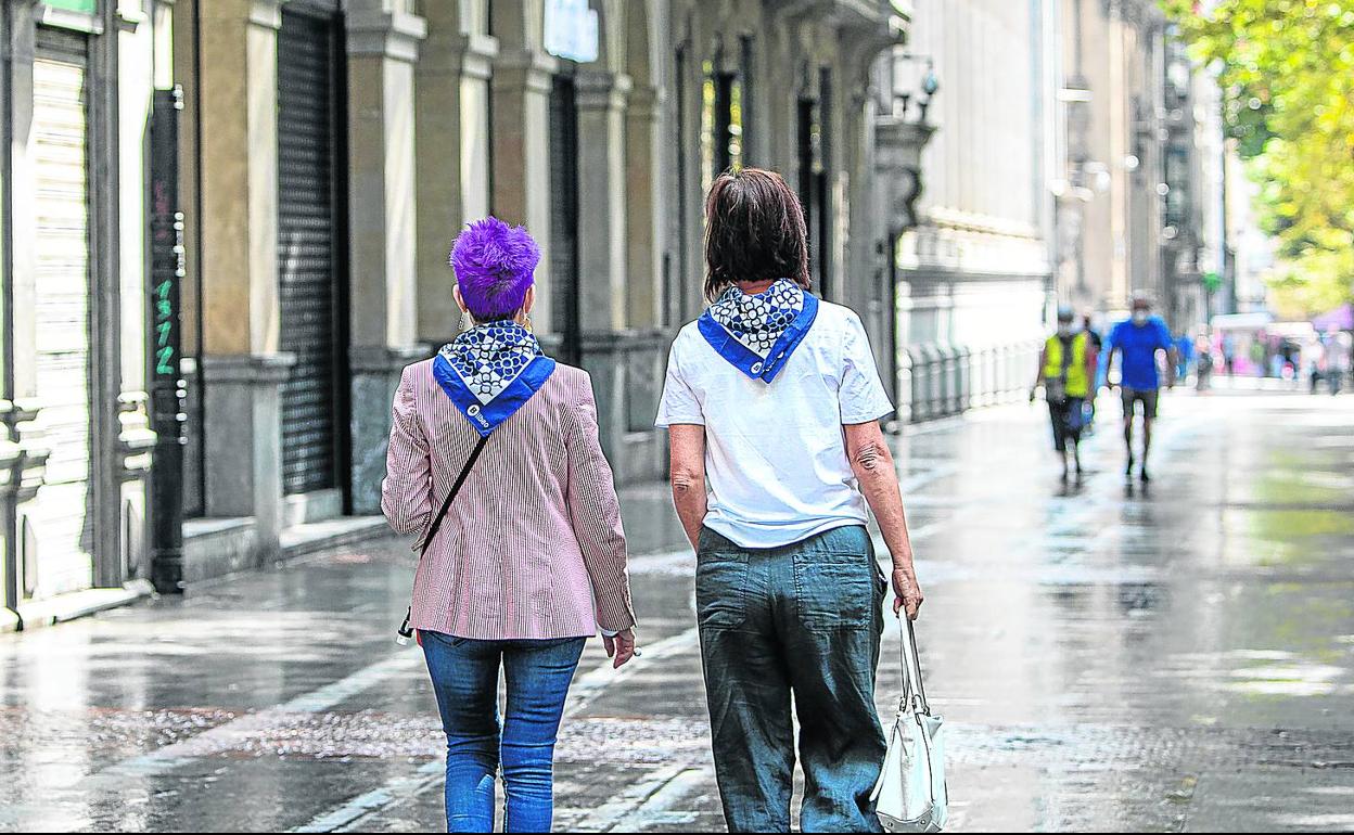 Dos mujeres caminan ayer por una Gran Vía casi desierta con el pañuelo de fiestas al cuello. 