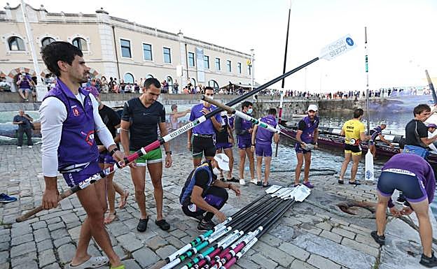 Previa. Los remeros de cogen los remos para saltar a la trainera.