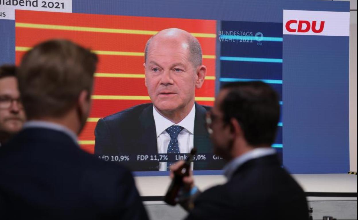 Seguimiento electoral en un pub alemán con Olaf Scholz en pantalla.