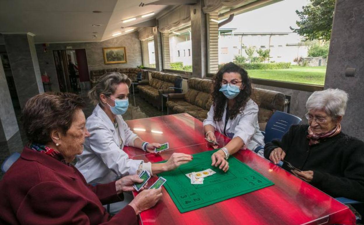 Ana Ramón y María Luisa Aranguren juegan a las cartas con dos usuarias de la residencia Juan Pablo I. 