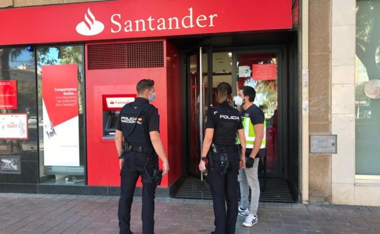 Tres agentes de la Policía Nacional frente a la sucursal bancaria donde se ha producido un atraco este martes.