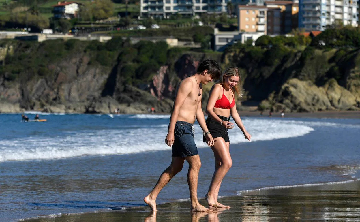 Dos jóvenes disfrutan del buen tiempo en la playa.