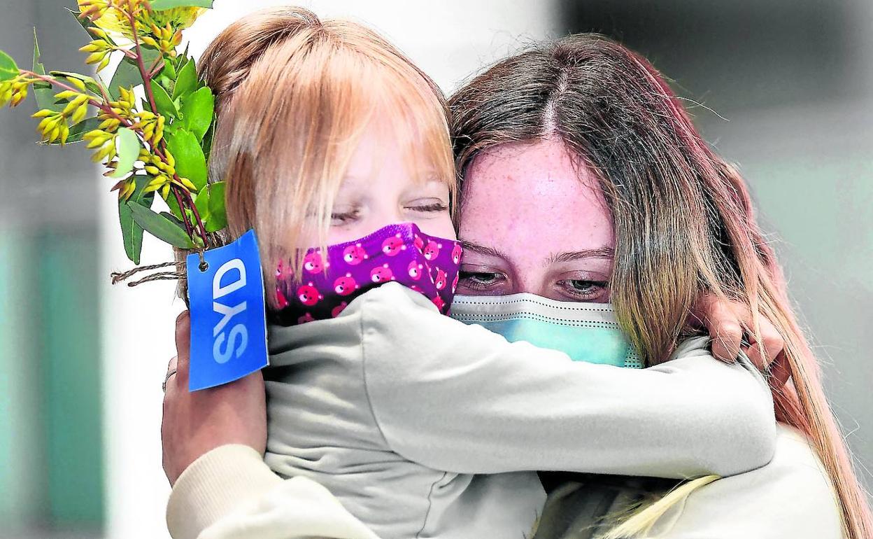 Miembros de una familia se abrazan en el aeropuerto internacional de Sídney tras permanecer cerradas las fronteras desde marzo del año pasado. 