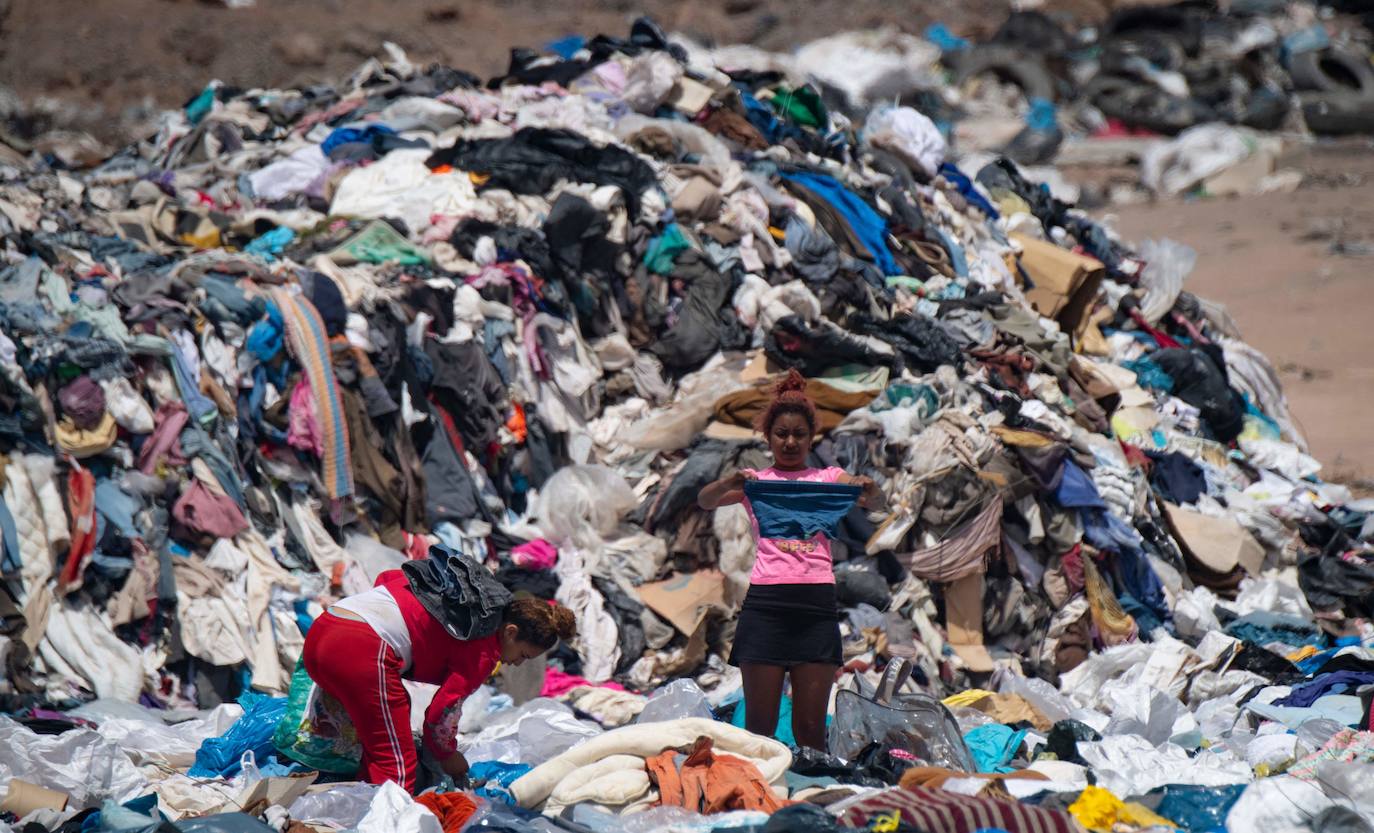 Una mujer escarba entre las toneladas de ropa usada.