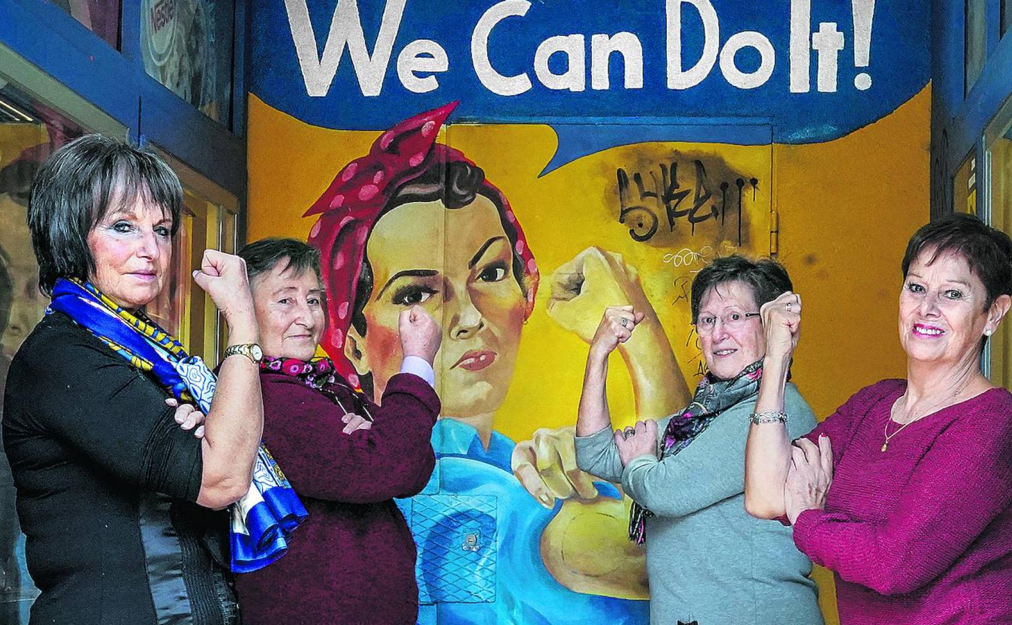 Karmele, Mariví, Rosa y Gloria, retratadas frente a una reproducción del icónico cartel de J. Howard Miller, reinterpretado como símbolo feminista. 