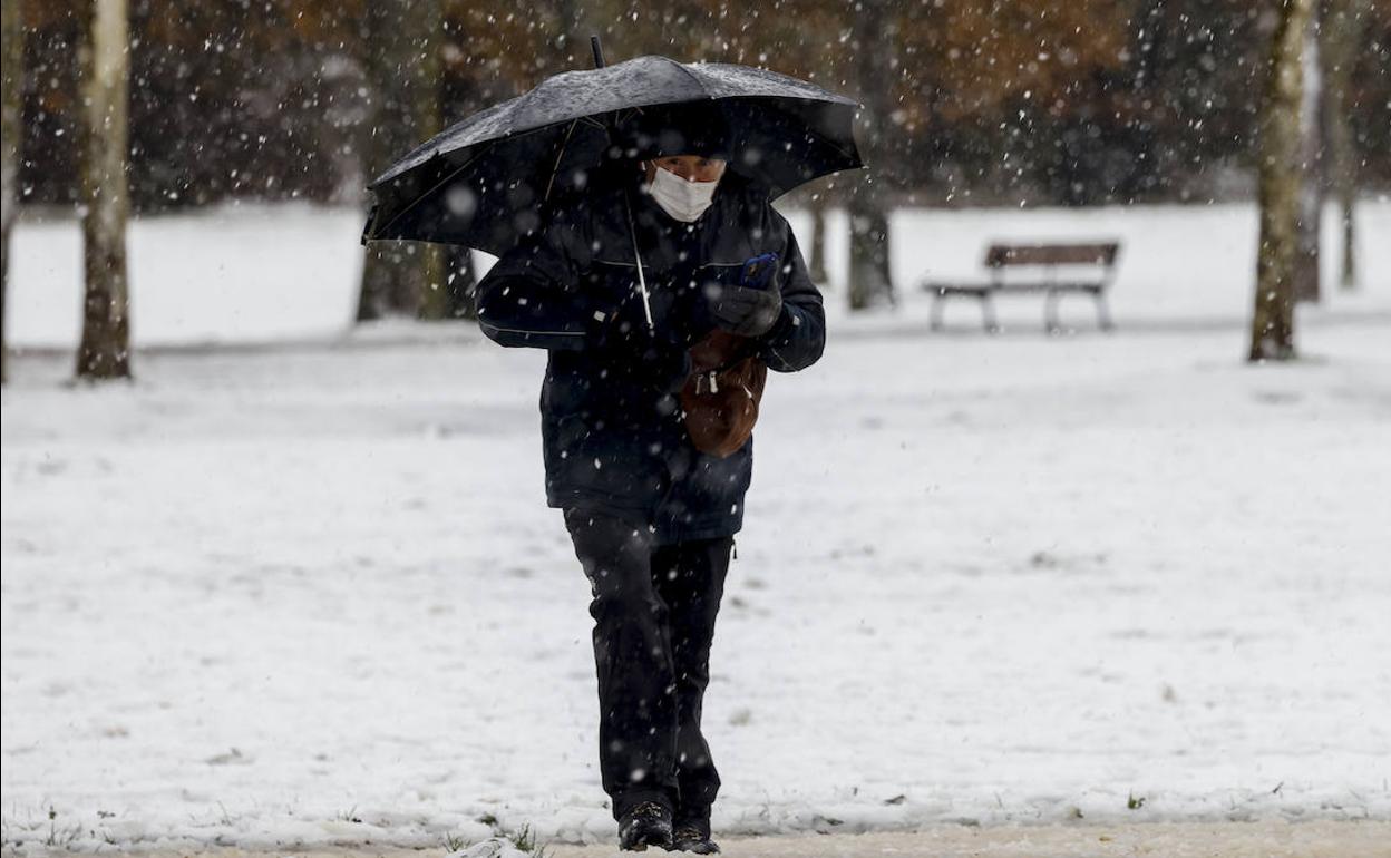 Un hombre se protege de la nieve mientras camina por Vitoria.