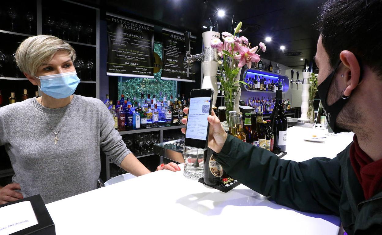 Un cliente muestra su pasaporte covid en el teléfono móvil.
